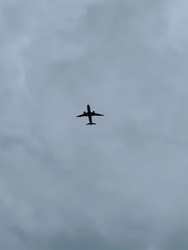 A low angle shot of an airplane flying in a cloudy sky