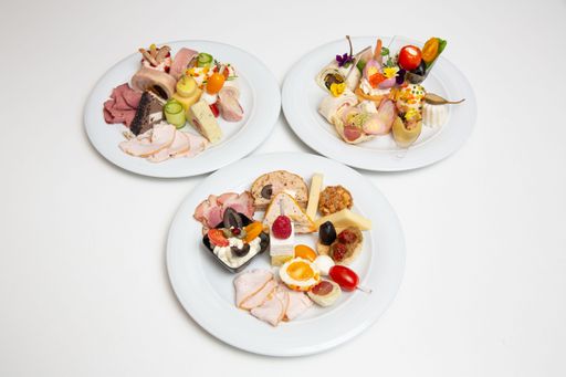 A closeup of plates with different types of cheese and ham.