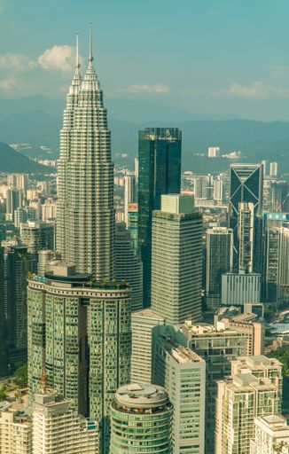 A vertical drone shot of the Petronas Towers of Kuala Lumpur, Malaysia seen from the KL Tower Menara