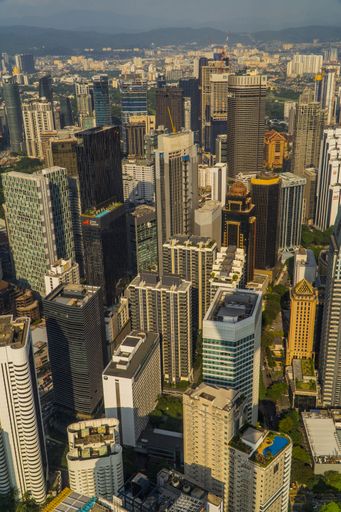 A vertical drone shot of the skyscrapers of Kuala Lumpur, Malaysia seen from the KL Tower Menara