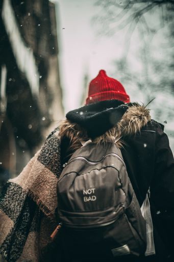 A back view of a young male walking under falling snow