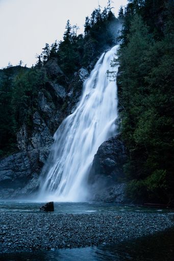 Vertical shot of a waterfall flowing over rocks covered with trees