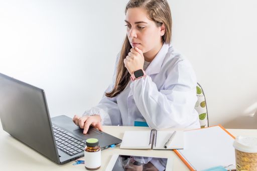 A young professional female doctor sitting in her consulting room writing a report or medical diagnosis