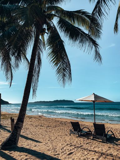 A view of a beach umbrella between two sun lounger near seashore