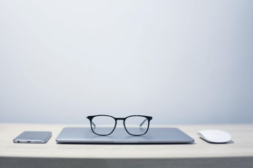 A closeup shot of optical glasses on the laptop with a smartphone and a mouse. Perfect for wallpaper