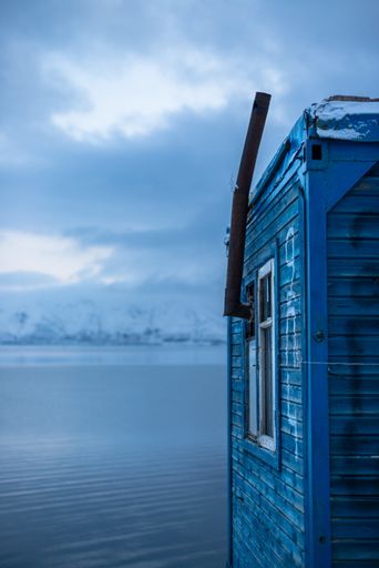 Little wooden house on a lake during winter with a chimney