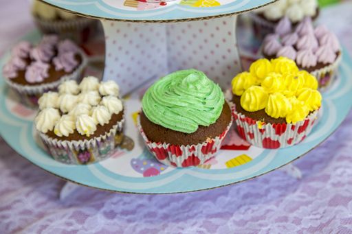 A closeup of cupcakes with colorful toppings on a tray under the lights