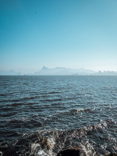 A vertical shot of a wavy sea under blue sky