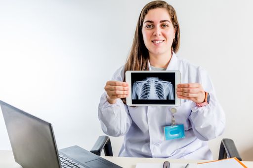 A professional young female doctor sitting in her consulting room showing an X-ray image on a tablet