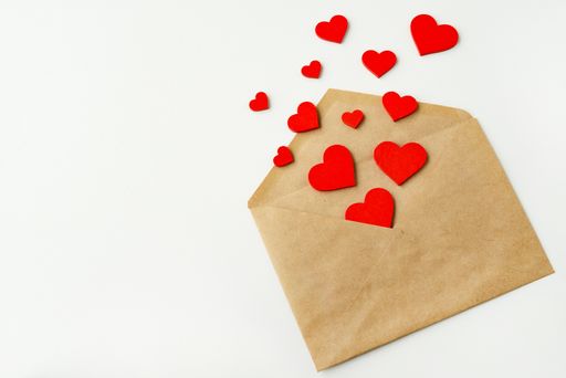 Open postal craft envelope and flying red hearts on a white background. 14 February concept. Valentines day greeting card, copy space