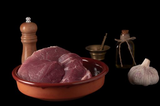 A closeup shot of raw meat with pepper, oil and garlic isolated on a black background