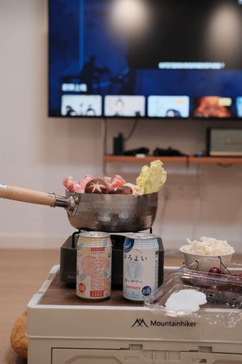 A vertical closeup of soda cand in front of a frying pan filled with various tasty food, on a stove