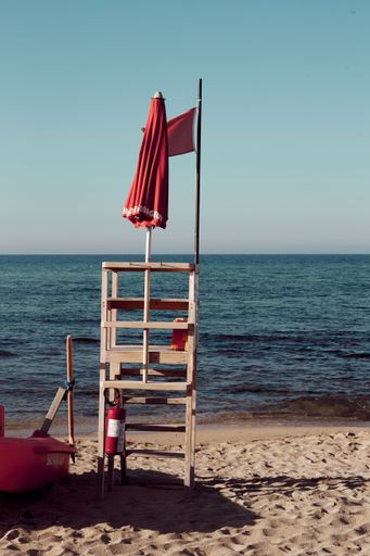 A vertical shot of a lifeguard's wooden chair on the shore of a beach
