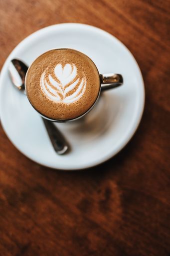 A beautifully made cappuccino served with flower art on the foam shot from an overhead view