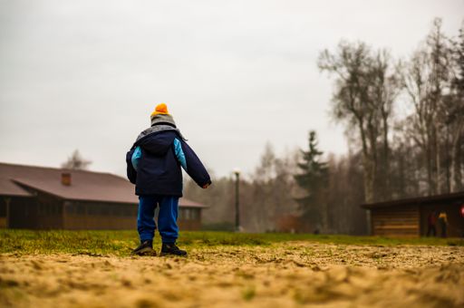 Young boy standing on sand by the Deczno lake on a cold winter day.
