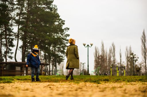 Woman and child standing on sand at the Deczno lake beach on a cold winter day.