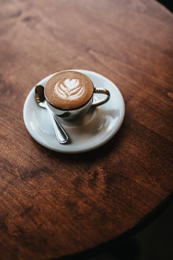 A beautifully made cappuccino served with flower art on the foam shot from an overhead view