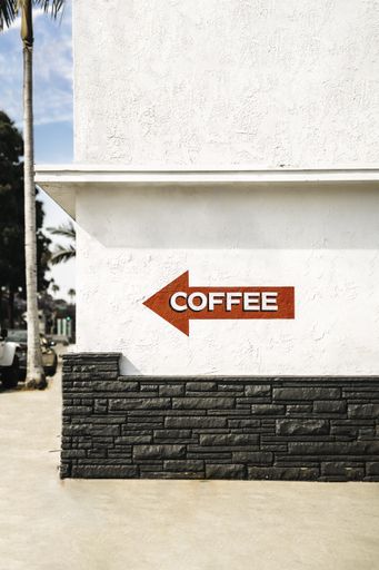 A red arrow sign on a white building with a writing "COFFEE" on it
