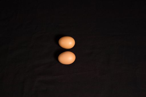 A top view of two brown eggs on a black surface