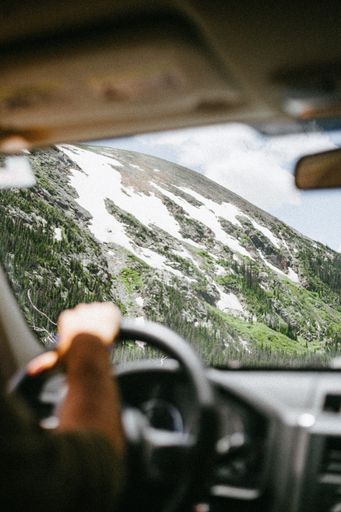 A part of a mountain covered with snow seen from the windscreen of a car