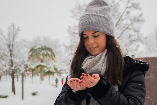 A young caucasian woman trying to catch snowflakes in a winter park
