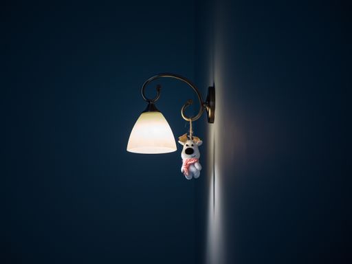A beautiful shot of a bright lamp on the wall with a hanging tiny toy