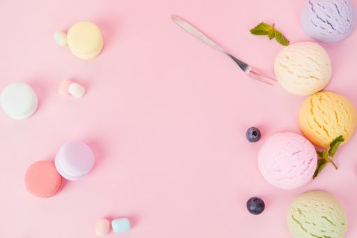 A top view of various flavored delicious ice cream scoops, macaroons and berries isolated on a pink background