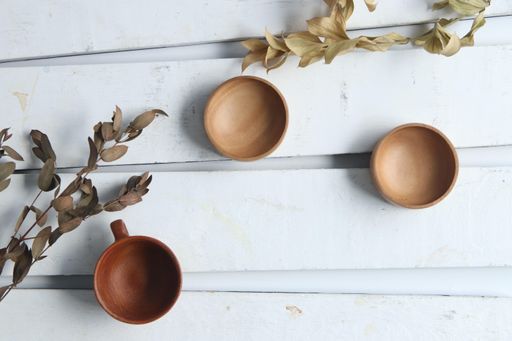 A top view of empty ceramic mug and saucers on white wooden background