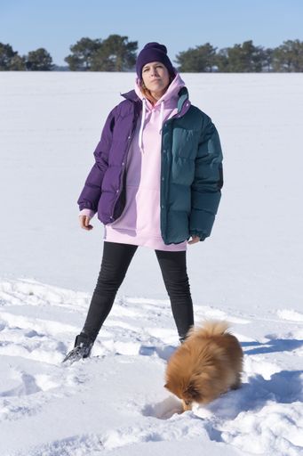 A shallow focus shot of a happy young female with a Pomeranian dog on the snow