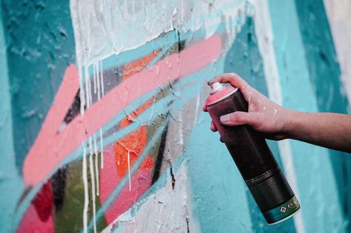 A closeup shot of an artist's hand holding a paint spray can for drawing graffiti on the wall