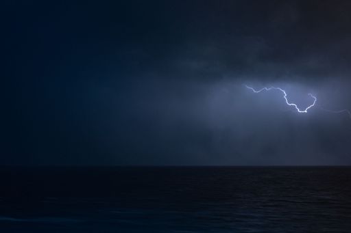 A scenic view of lightning visible in the sky during a thunderstorm at night