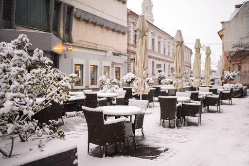 A beautiful outdoor cafe covered in snow near the old buildings