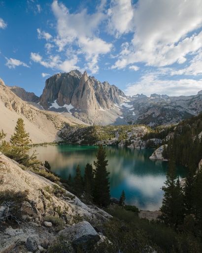 A vertical shot of a wonderful calm lake with mountains and green forests