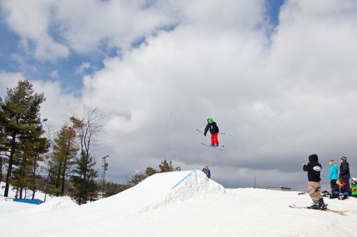 A professional skier making a jump high into the air during freestyle skiing competition with spectators watching