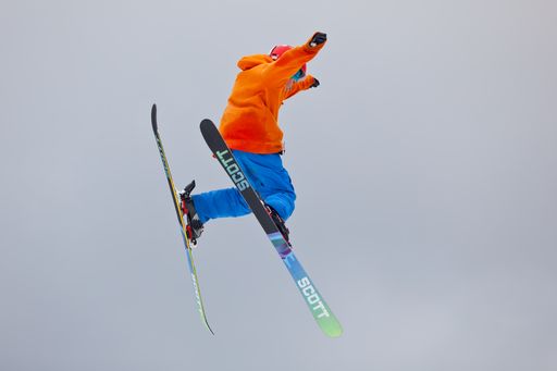 A young skier making a jump high into the air during freestyle skiing competition.
