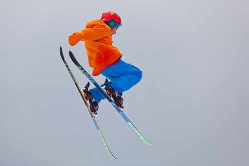 A young skier making a jump high into the air during freestyle skiing competition.