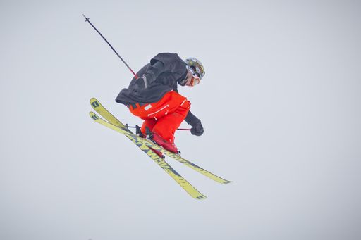 A professional skier making a jump high into the air during freestyle skiing competition.
