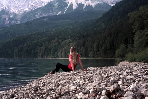 A female tourist observing the view of greenery-covered hills and mountains near a village in Austria