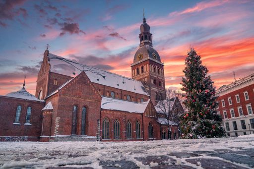 A low angle shot of beautiful sunset over a decorated Christmas tree in the Dome Square in Riga