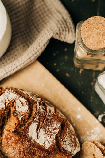 A vertical shot of a loaf of fresh bread on a wooden board