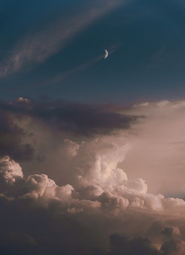 A vertical shot of wonderful clouds and a new moon in the sky