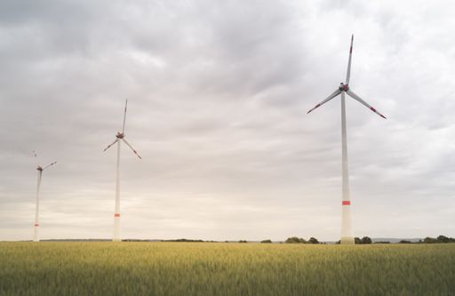 A shot of wind turbines in the open green field on a gloomy day