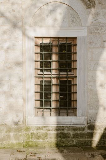 A vertical shot of an old window in a rusty white wall