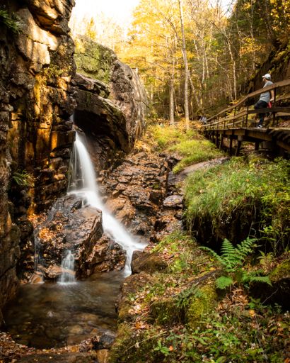 A beautiful shot of Flume Gorge Trail with waterfall and wooden bridge in Franconia Notch State Park.