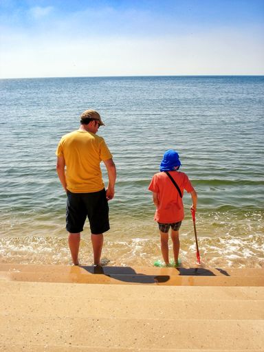 A close-up of a father and his young son standing on a beach