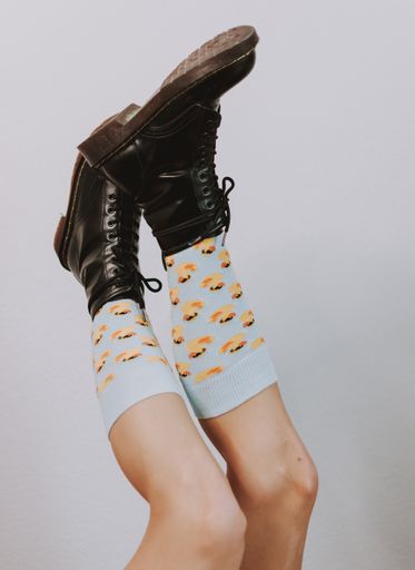 A closeup of female legs in fashionable leather black boots and colorful socks