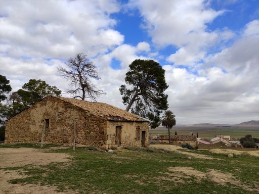 A fantastic shot of an old house with a red roof and dry trees on a cloudy sky background
