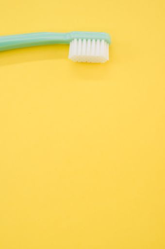 A vertical shot of turquoise toothbrush on a yellow surface for a copy space
