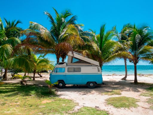 A scenic view of a van on a beach near palm trees, Mahahual village, coast of Quintana Roo state in Mexico