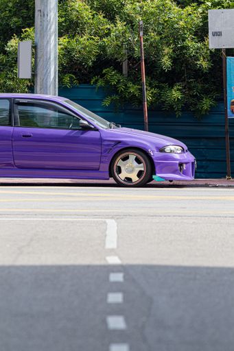 A vertical shot of a purple car on roa